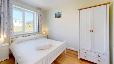 a bedroom with a white bed and a window at G07 Tweenbanx, Riviere Towans in Hayle