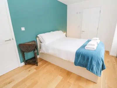 a bedroom with a bed with white sheets and blue walls at James' Place in Falmouth