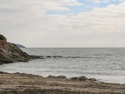 a beach with rocks and the ocean on a cloudy day at James' Place in Falmouth