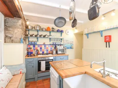 a kitchen with blue cabinets and a sink at Crab Pot Cottage in Helston