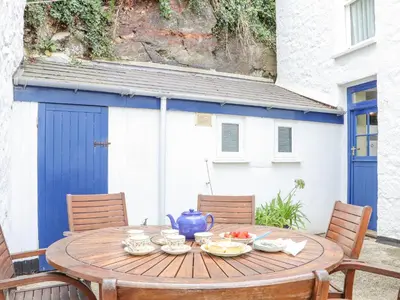 a wooden table with bowls of fruit on a patio at Crab Pot Cottage in Helston