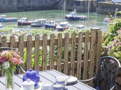a table with a blue tea pot on it with boats in the water at Crab Pot Cottage in Helston