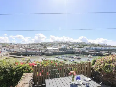 a patio with a table with a view of a harbor at Crab Pot Cottage in Helston