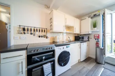 a kitchen with white cabinets and a dishwasher at Newquay Sunset & Sea View Apartment in Town Centre in Newquay