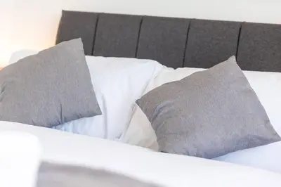 a bed with two gray pillows on top of it at Newquay Sunset & Sea View Apartment in Town Centre in Newquay