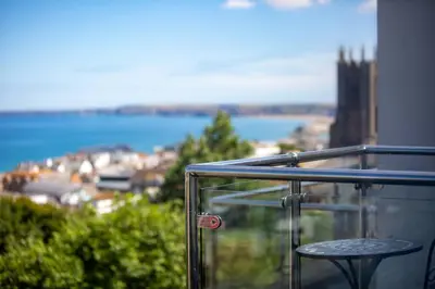 a balcony with a table and a view of the water at Newquay Sunset & Sea View Apartment in Town Centre in Newquay