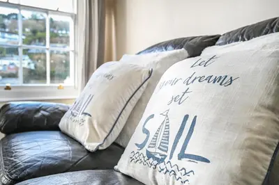 a couch with two pillows on top of it at 3Bed Apartment Sleeps 5- Parking Wifi Near Beach in Looe