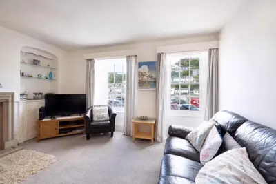 a living room with a leather couch and a television at 3Bed Apartment Sleeps 5- Parking Wifi Near Beach in Looe