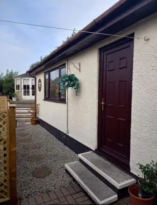 a house with a brown door and a potted plant at Self Contained Garden Annexe in Bodmin in Bodmin