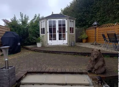 a dog sitting in front of a small greenhouse at Self Contained Garden Annexe in Bodmin in Bodmin