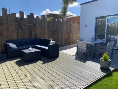 a patio with a blue couch and a table at Littlecroft, Hollywell Bay by Together Travel - Luxury Seaside Cottage Retreat in Holywell Bay
