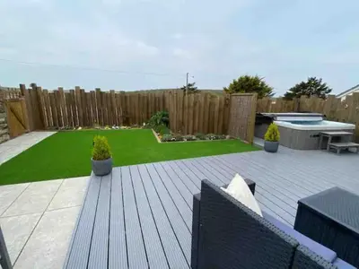 a backyard with a wooden deck and a garden at Littlecroft, Hollywell Bay by Together Travel - Luxury Seaside Cottage Retreat in Holywell Bay
