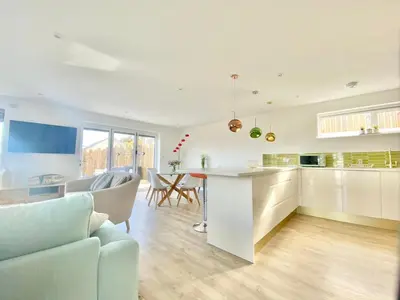 a kitchen and living room with a table and chairs at Littlecroft, Hollywell Bay by Together Travel - Luxury Seaside Cottage Retreat in Holywell Bay