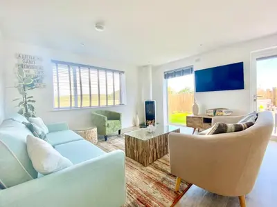 a living room with a blue couch and chairs at Littlecroft, Hollywell Bay by Together Travel - Luxury Seaside Cottage Retreat in Holywell Bay