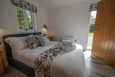 a bedroom with a bed with white sheets and pillows at Olverstone Lodge, a beautiful Cornish lodge with wood burner & garden in St Austell