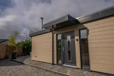 a small house with a wooden deck in front of it at Olverstone Lodge, a beautiful Cornish lodge with wood burner & garden in St Austell