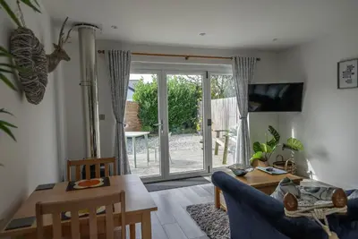 a living room with a blue couch and a table at Olverstone Lodge, a beautiful Cornish lodge with wood burner & garden in St Austell