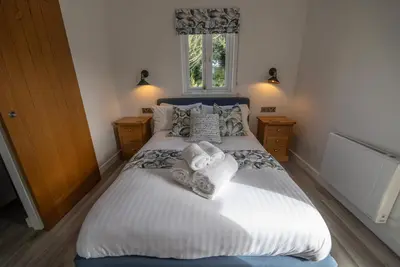 a bedroom with a large bed with white sheets and pillows at Olverstone Lodge, a beautiful Cornish lodge with wood burner & garden in St Austell