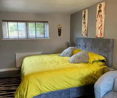 a bedroom with a large bed with a yellow blanket at Twin Gates Annexe in Falmouth