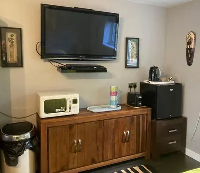 a tv on the corner of a room with a microwave at Twin Gates Annexe in Falmouth