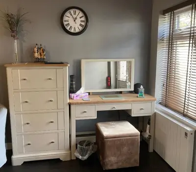 a bedroom with a desk and a clock on the wall at Twin Gates Annexe in Falmouth