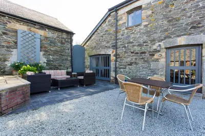 a patio with a table and chairs and a building at Super Spacious Country house pet/party friendly. in Newquay