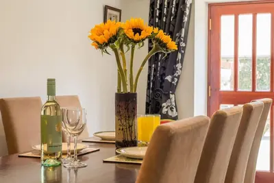 a dining room table with a vase of sunflowers on it at Super Spacious Country house pet/party friendly. in Newquay