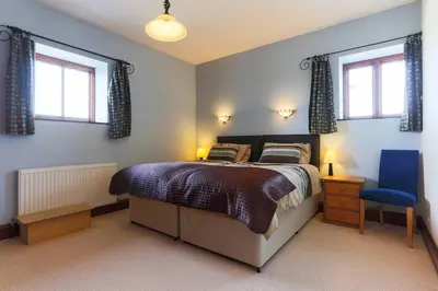 a bedroom with a bed and a blue chair at Super Spacious Country house pet/party friendly. in Newquay