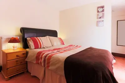 a bedroom with a bed and a night stand with a lamp at Super Spacious Country house pet/party friendly. in Newquay