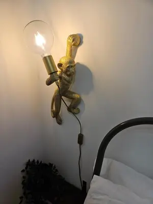 a lamp with a monkey on the wall next to a bed at 