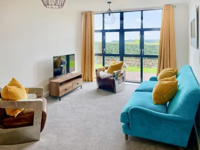 a living room with a blue couch and a large window at Number Six in St Austell