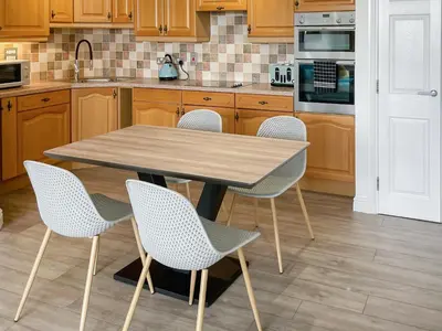 a kitchen with a wooden table and chairs at Number Six in St Austell