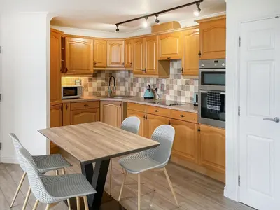 a kitchen with wooden cabinets and a wooden table and chairs at Number Six in St Austell
