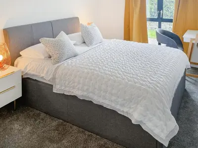 a bed with a white comforter and pillows on it at Number Six in St Austell