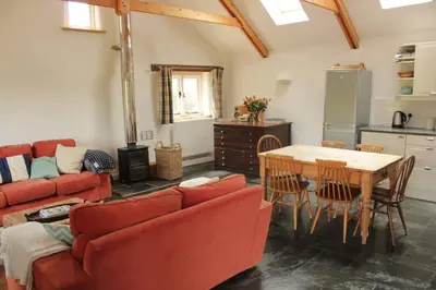 a living room with a red couch and a table at Kiddlywink Cottage in Saint Columb Major