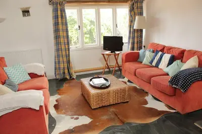 a living room with a red couch and a largeumedumedumedumed at Kiddlywink Cottage in Saint Columb Major