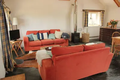 a living room with two red couches and a television at Kiddlywink Cottage in Saint Columb Major
