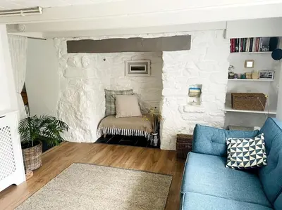 a living room with a blue couch and a stone wall at Coombe Cottage in St. Agnes