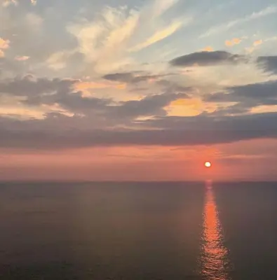 a sunset over the ocean with the sun in the sky at Coombe Cottage in St. Agnes