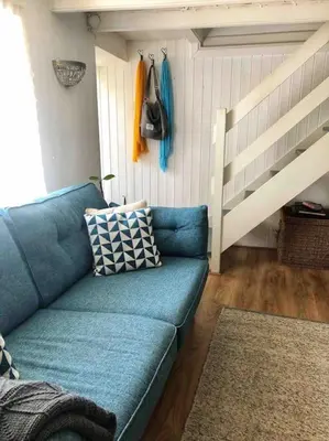 a blue couch in a living room with a ladder at Coombe Cottage in St. Agnes