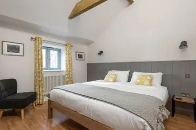 a bedroom with a large bed and a chair at Gilliflower 1 bedroom cottage at Trethwale Barns Holiday Home in Saint Keyne