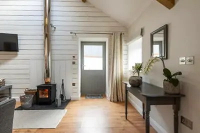 a living room with a wood stove and a door at Gilliflower 1 bedroom cottage at Trethwale Barns Holiday Home in Saint Keyne