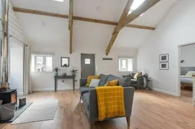 a living room with a gray couch and a yellow blanket at Gilliflower 1 bedroom cottage at Trethwale Barns Holiday Home in Saint Keyne
