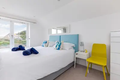 a bedroom with two beds and a yellow chair at The Beach House in Wadebridge