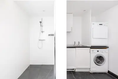 a white kitchen with a washing machine and a sink at The Beach House in Wadebridge