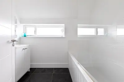 a white bathroom with a shower and a sink at The Beach House in Wadebridge