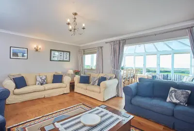 a living room with blue and white furniture and windows at Little Seawynds in Port Isaac