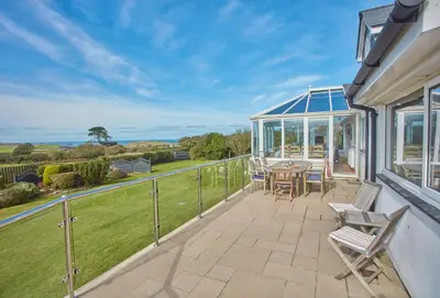 a patio with a table and chairs on a balcony at Little Seawynds in Port Isaac