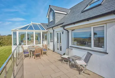 a patio with a table and chairs on a balcony at Little Seawynds in Port Isaac