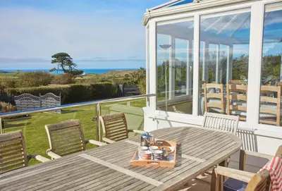a table and chairs on a porch with a view of the ocean at Little Seawynds in Port Isaac